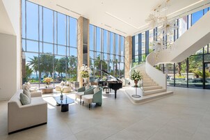 A spacious lobby with a grand piano, comfortable seating, and a view of the outdoors.