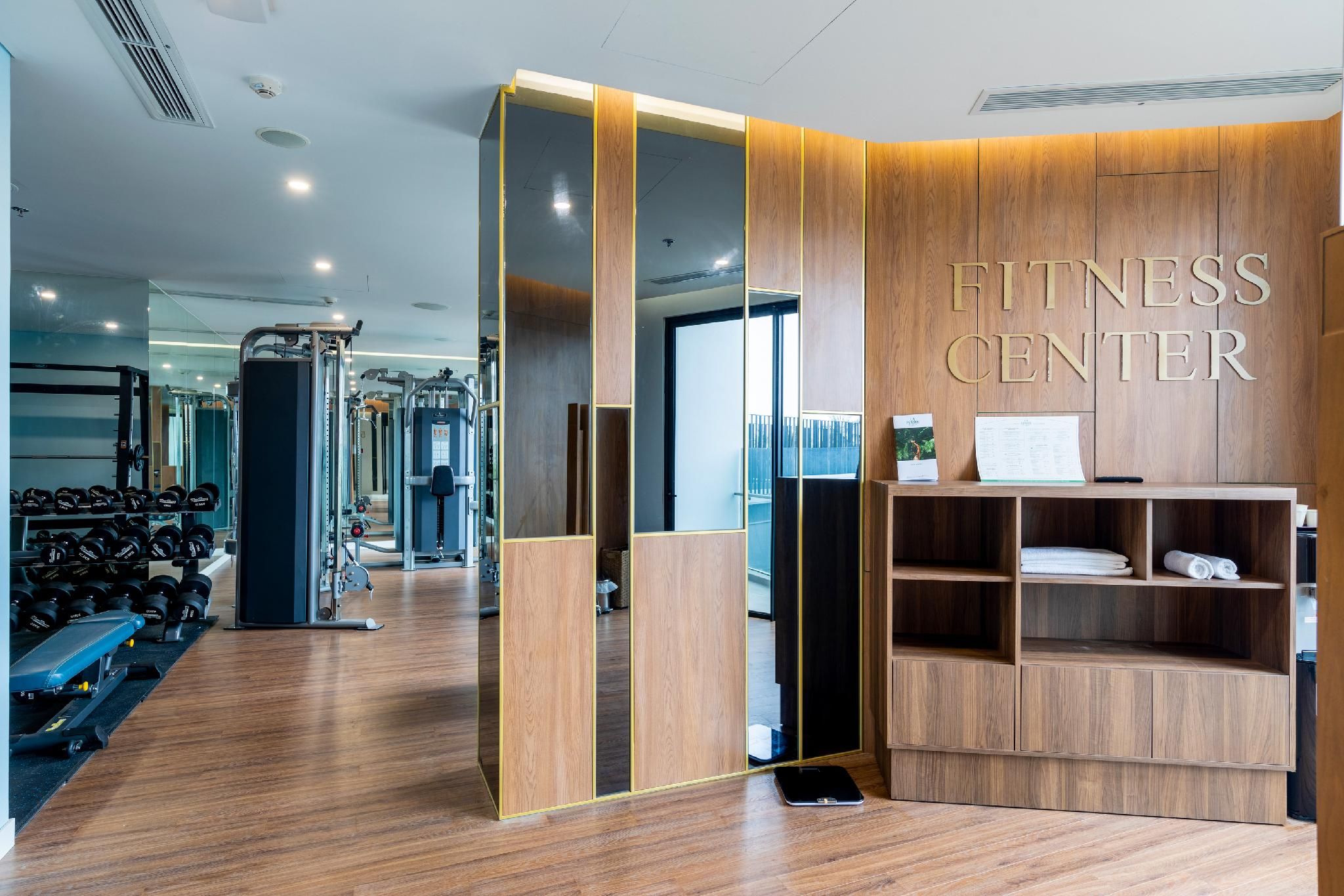 Un gimnasio con paredes de espejo, equipo de ejercicio y una zona de recepción.