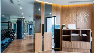 Un gimnasio con paredes de espejo, equipo de ejercicio y una zona de recepción.
