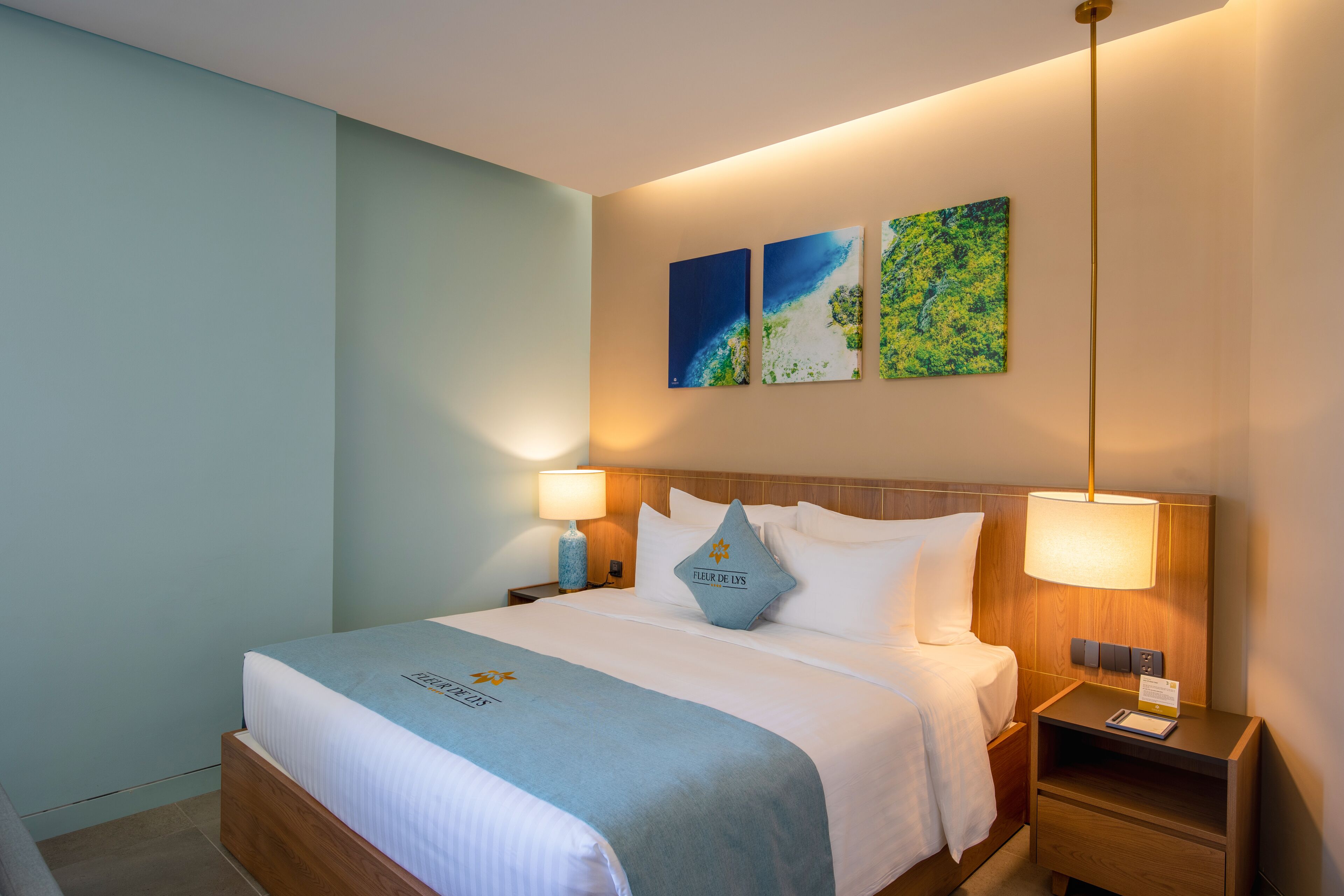Ein Hotelzimmer mit Bett, zwei Nachttischlampen, einem Nachttisch und einem Bild an der Wand.
