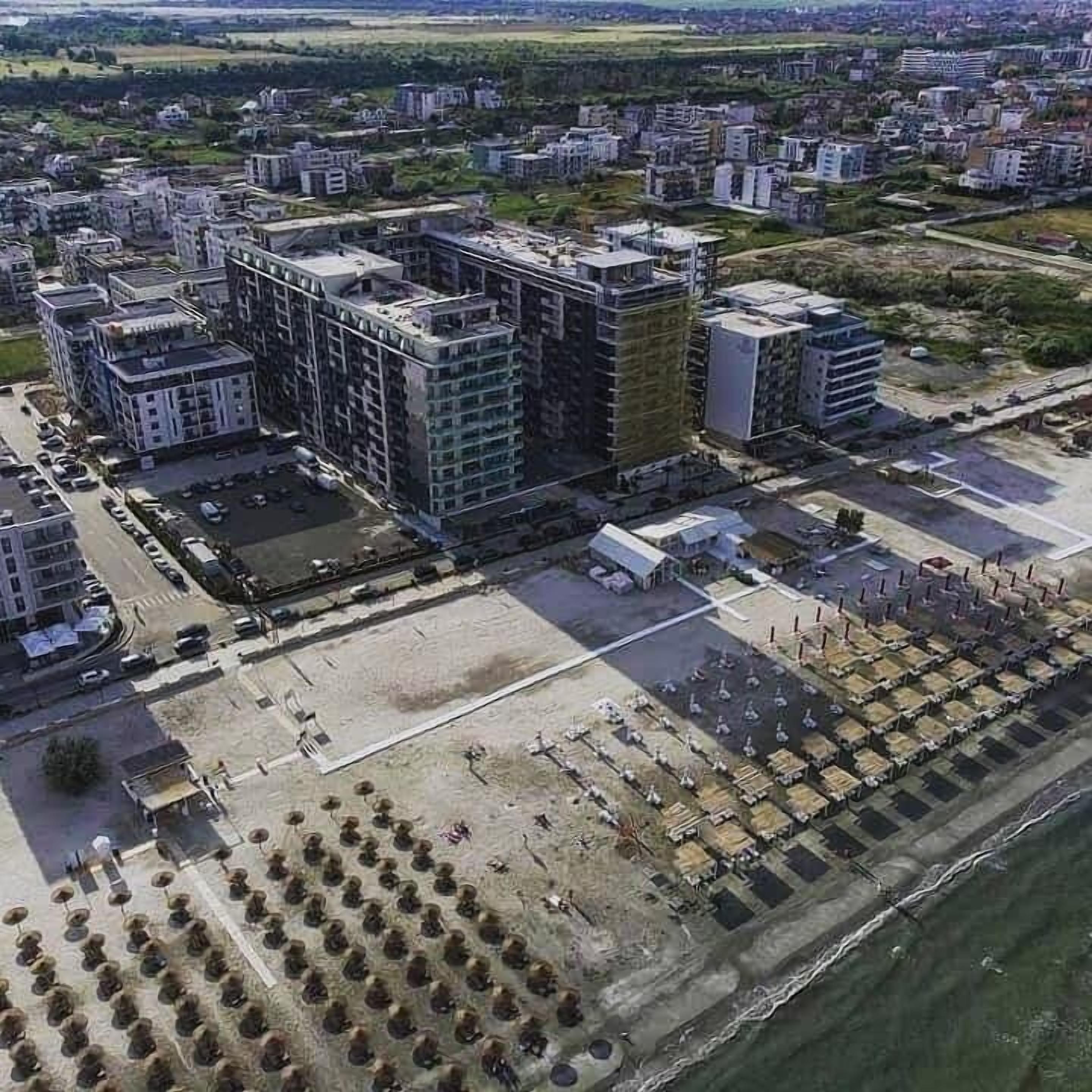 Vista aérea de una zona urbana moderna con rascacielos, una plaza central abierta y un frente marítimo.