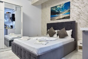 A modern hotel room with a large bed, a painting of a beach scene, and a bathroom visible through an open door. - Resort Stefan (Navodari)