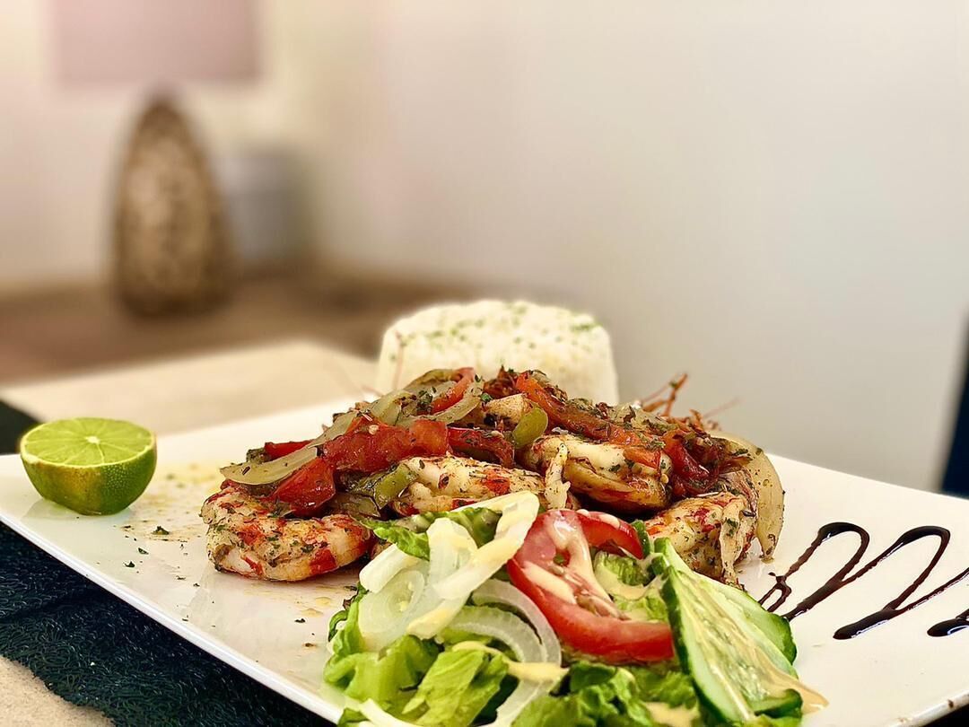 Une assiette de poulet grillé, accompagné de légumes et d’un quartier de citron vert.