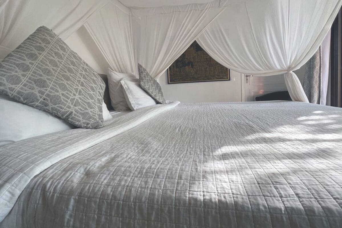 Ein Bett mit einer gesteppten Bettdecke, zwei Kissen und einem Baldachin.