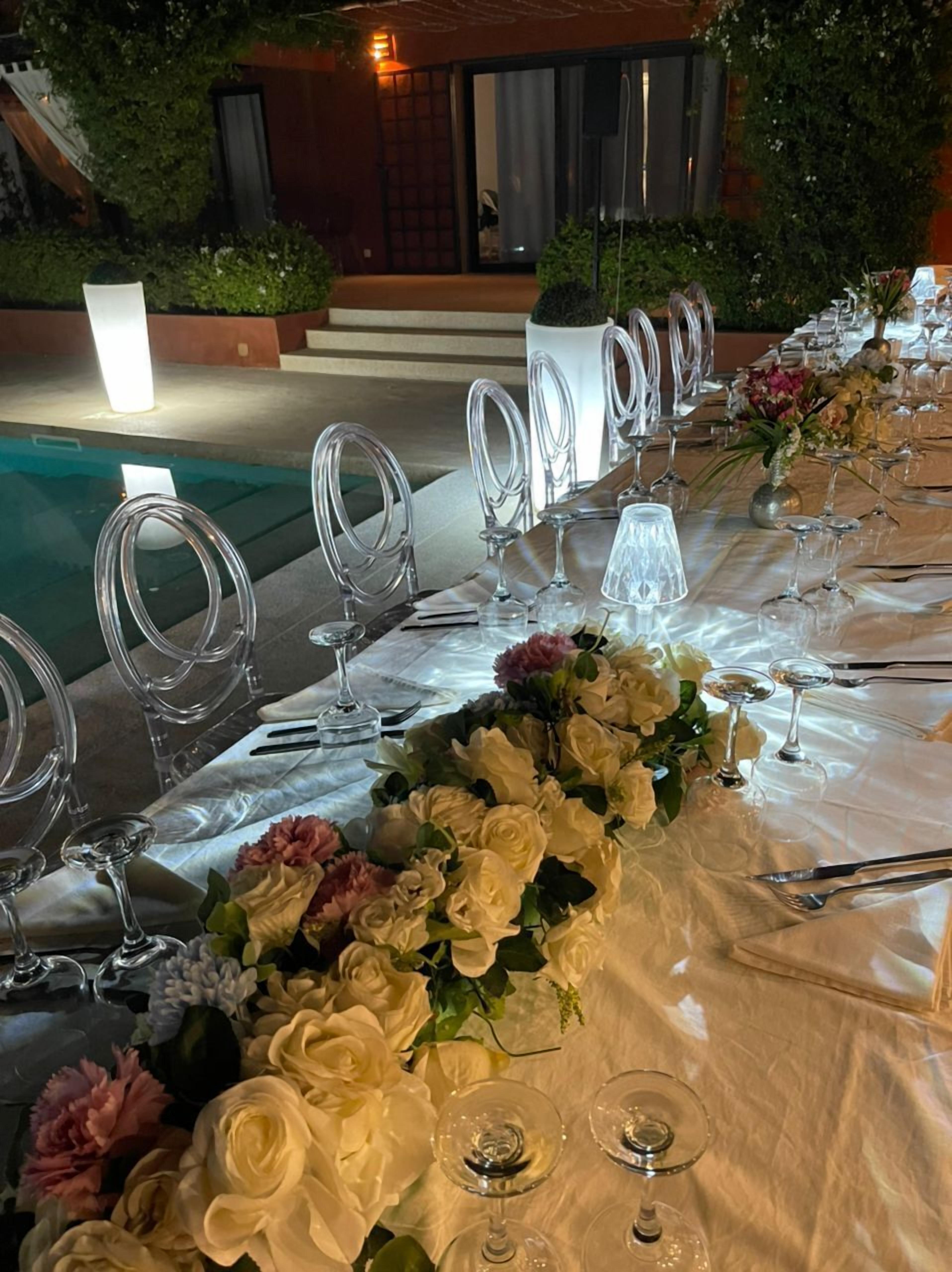 A long dining table set for a formal event, with clear glassware and floral centerpieces.