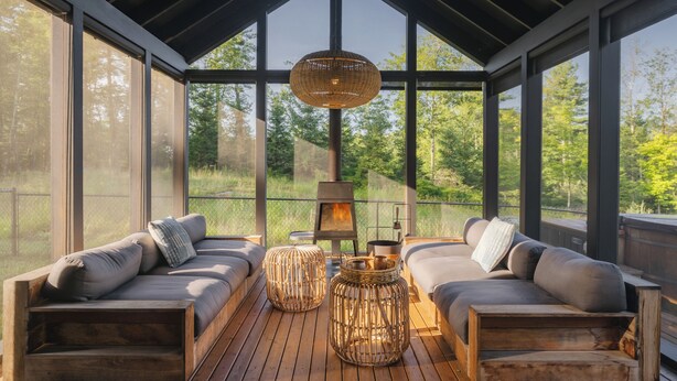A cozy outdoor seating area with two sofas, wicker ottomans, and a hanging light fixture. - A Retreat @ Hudson Woods With Pool & Hot Tub (Kerhonkson)
