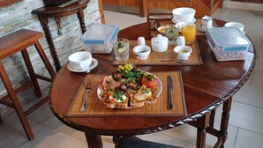 A wooden dining table with a breakfast setup including toast, eggs, and vegetables, surrounded by various kitchen items and containers.