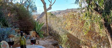 A round table with two chairs, a bottle of wine, and two wine glasses on a tiled patio.