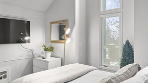 A bedroom with a large window, a bedside table with a lamp, a mirror, and a plant. - Great views from condo w/free winter shuttle (Brian Head)