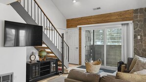 A modern living room with a staircase, a flat-screen TV, a globe, and a basket. - Great views from condo w/free winter shuttle (Brian Head)