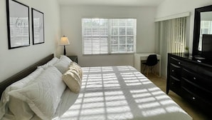 Ein Schlafzimmer mit einem Bett, einem Schreibtisch, einem Stuhl, einer Kommode und zwei gerahmten Bildern an der Wand.