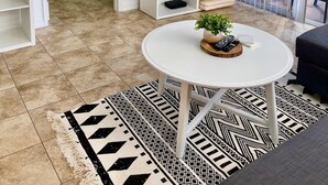 A modern living room with a television, a coffee table with a plant, and a patterned rug. - 340B - Boca Retreat w/ Pool, Parking, Near Evert Tennis & Shops (Boca Raton)