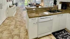 A modern kitchen with white cabinetry, a granite countertop, and a large island with a sink. - 340B - Boca Retreat w/ Pool, Parking, Near Evert Tennis & Shops (Boca Raton)