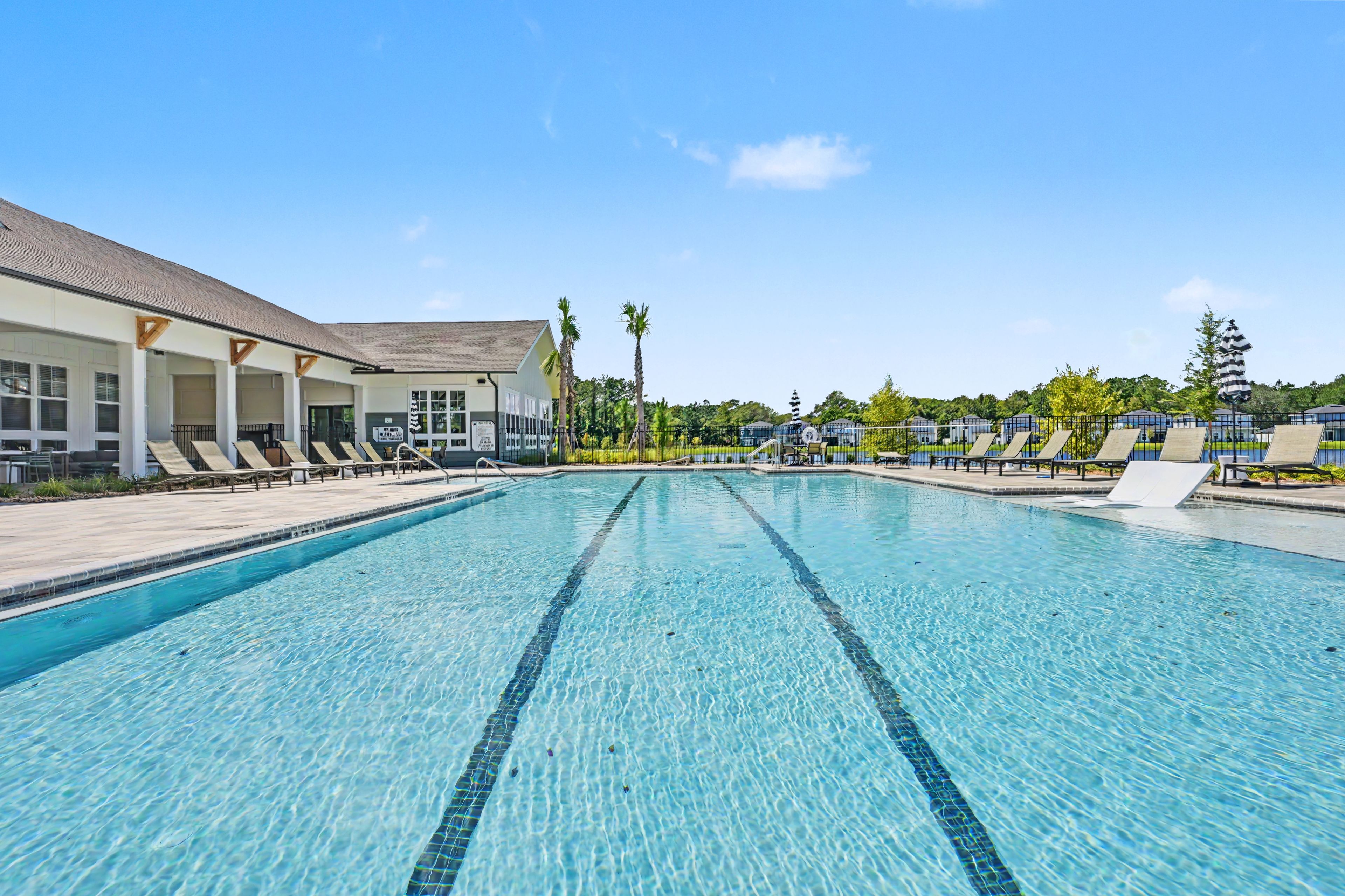 A swimming pool with lounge chairs and a covered area with a sign.