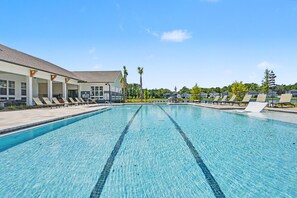 A swimming pool with lounge chairs and a covered area with a sign.