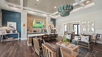 A spacious lobby with a bar area, seating arrangements, and a large screen displaying a sports event.