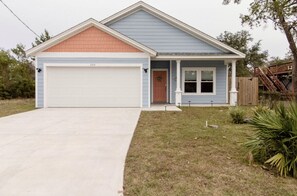Une maison de plain-pied avec un garage, un porche à l’avant et un petit jardin devant.