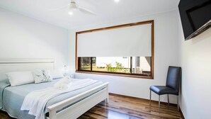 Ein Schlafzimmer mit einem Bett, einem Sessel, einem Deckenventilator und einem Fenster mit Blick.