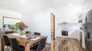 A modern kitchen with white cabinets, a built-in oven, and a stainless steel refrigerator.