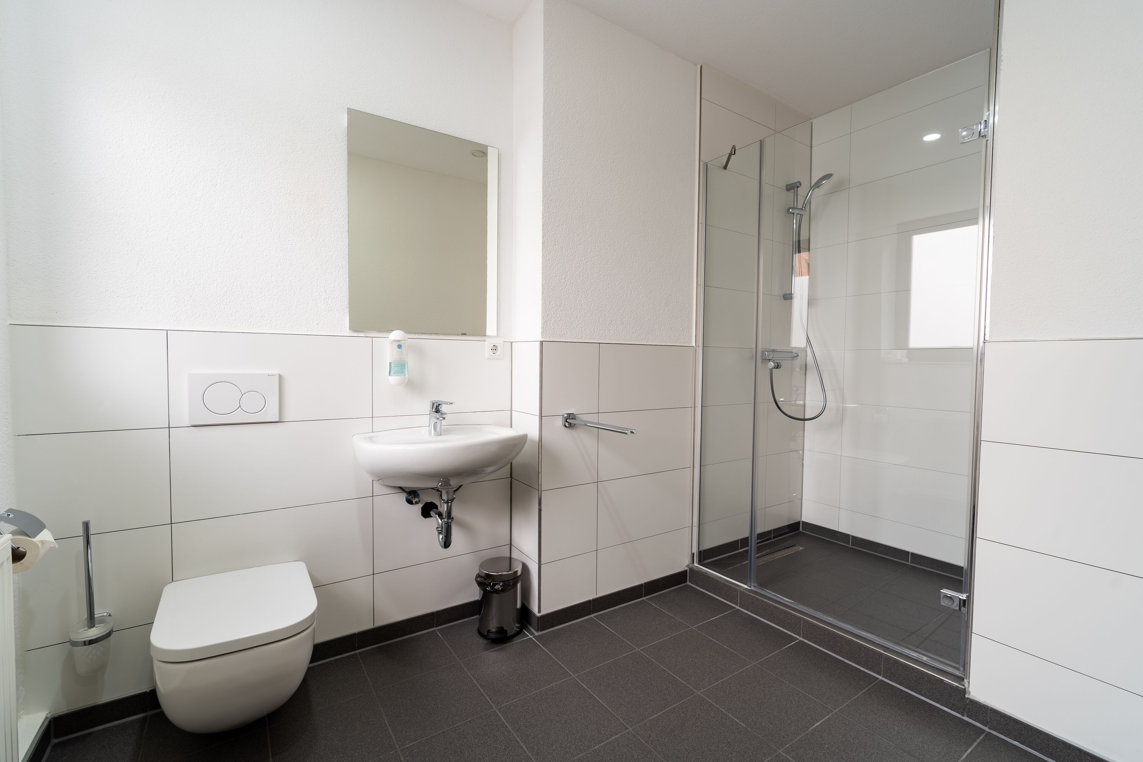 Ein modernes Badezimmer mit Toilette, Waschbecken und einer Duschkabine.