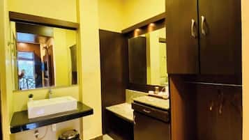 A bathroom with a sink, mirror, cabinets, and a trash bin.