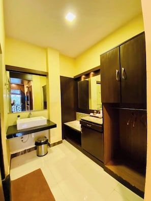 A bathroom with a sink, mirror, cabinets, and a trash bin.