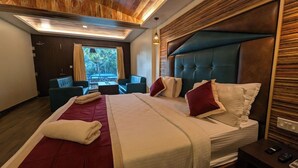 Moderni hotellihuone, jossa on suuri sänky, oleskelualue ja näkymä ulos.