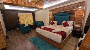 Hotellihuone, jossa on suuri sänky, työpöytä, tuoli ja sohva.