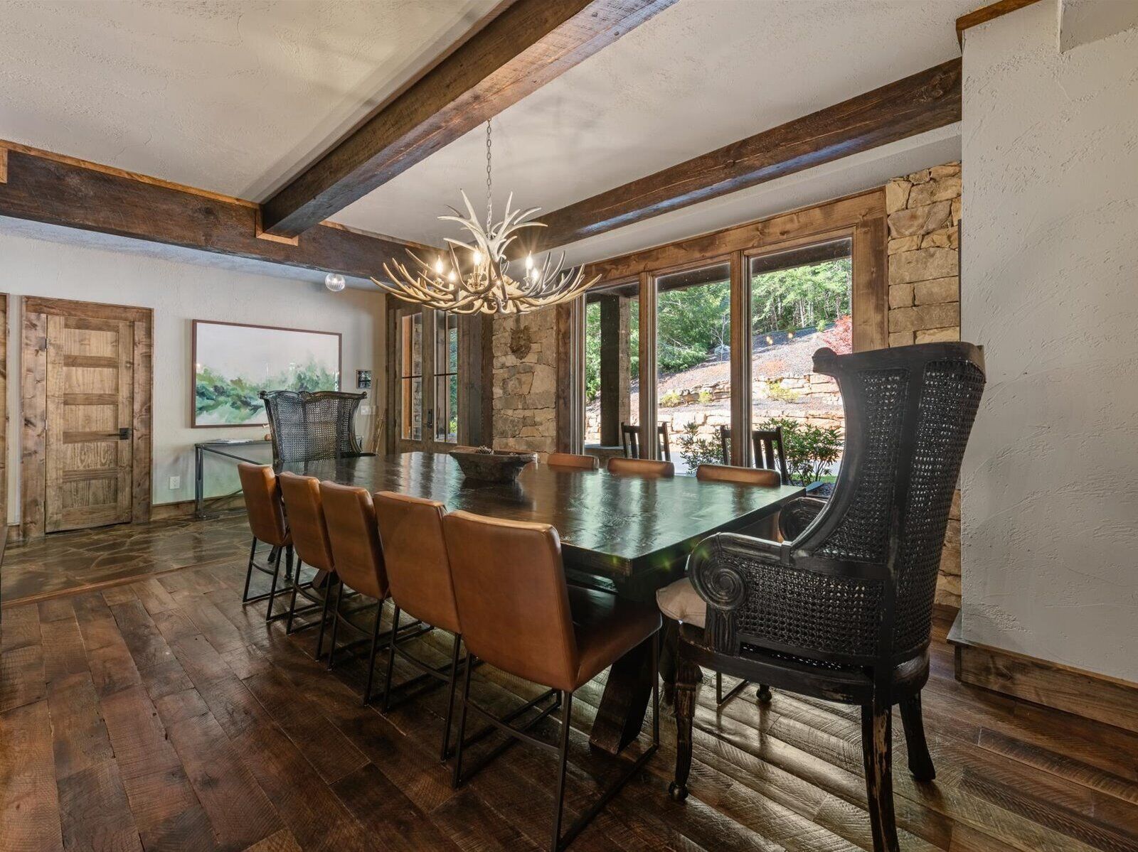A dining area with a large table, six chairs, and a chandelier.