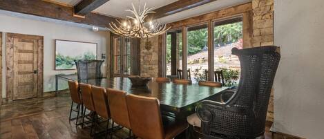 A dining area with a large table, six chairs, and a chandelier.