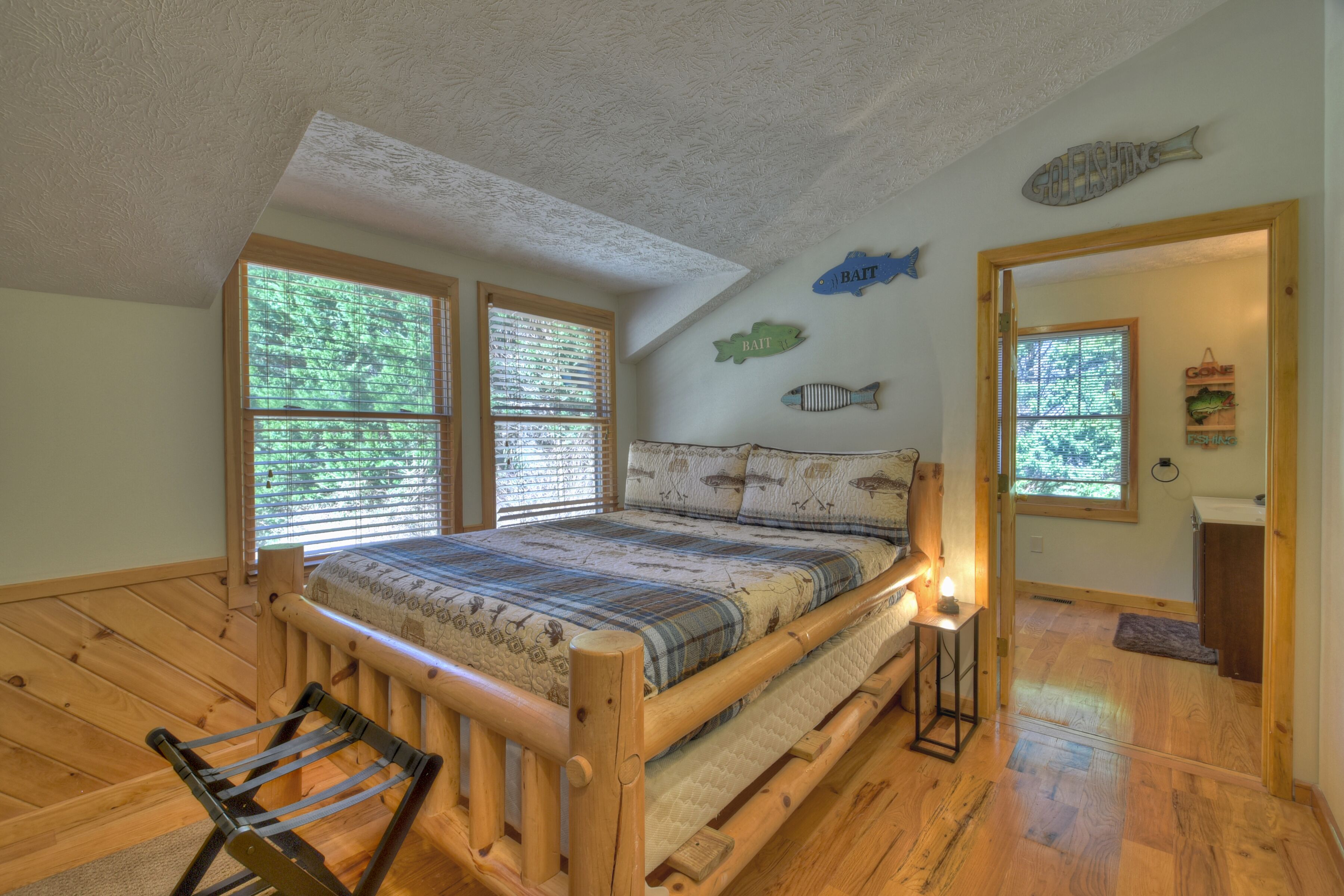A bedroom with a wooden bed, two windows, and fish-themed wall decorations.