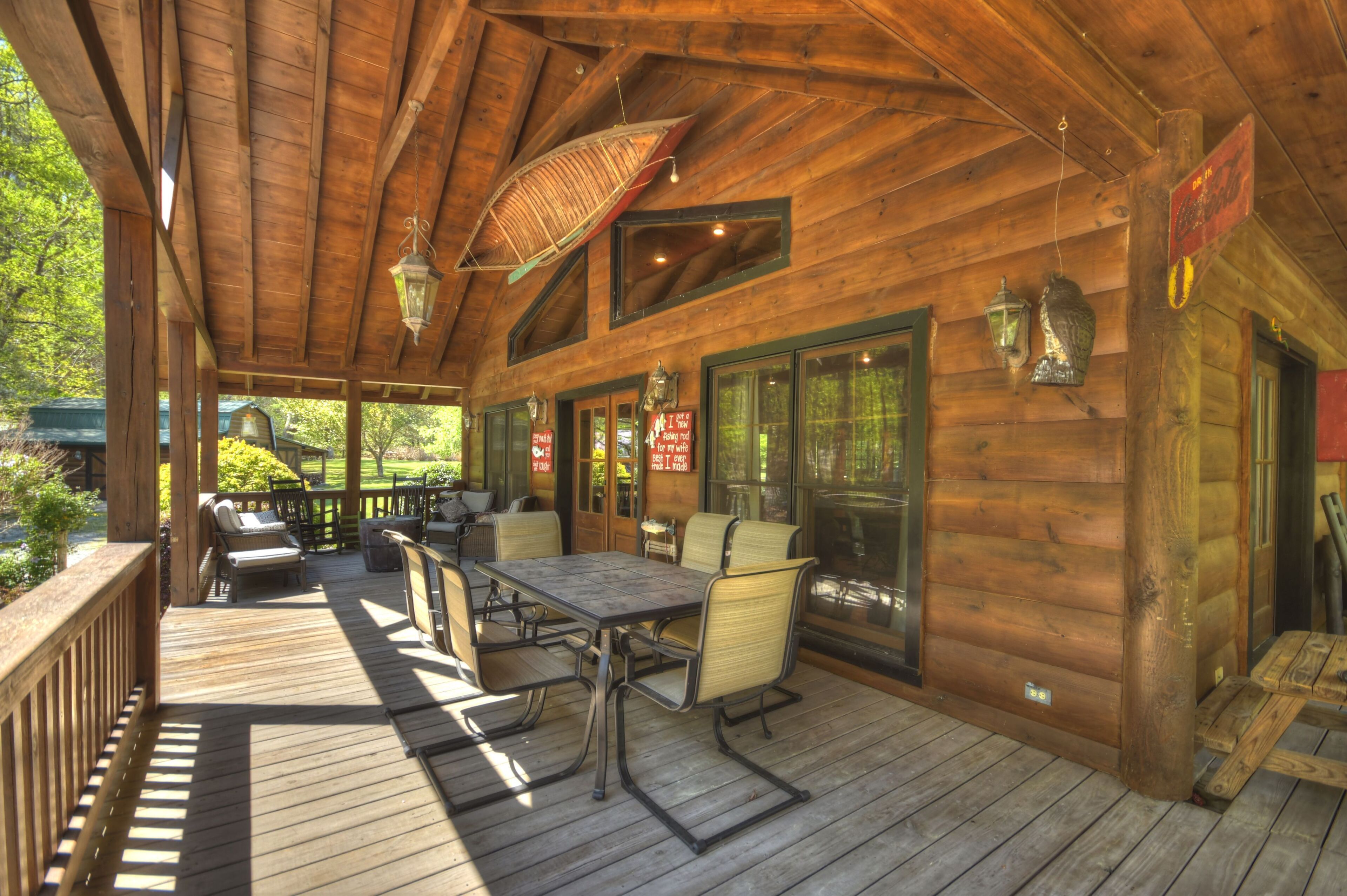 A wooden deck with outdoor seating, large windows, and hanging lanterns.