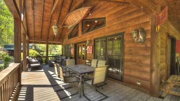 A wooden deck with outdoor seating, large windows, and hanging lanterns.