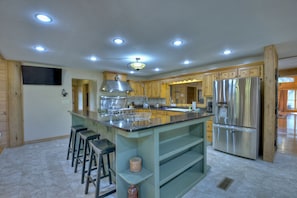 A spacious kitchen with a central island, stainless steel appliances, and wooden cabinetry.