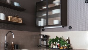 A modern kitchen with dark wood cabinets, a stainless steel sink, and a built-in range hood. - Tweed Hotell Skaftö (Fiskebackskil)