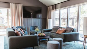 A modern living room with a sofa set, ottomans, a coffee table, and a flat-screen TV. - Tweed Hotell Skaftö (Fiskebackskil)