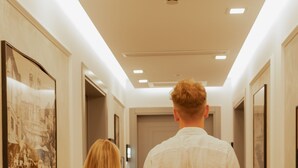 A hallway with framed pictures on the walls, a ceiling light, and a door at the end. - GRANDI 32  Boutique Residence (Segrate)