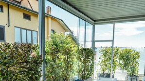 A covered outdoor seating area with modern chairs and planters of various plants. - GRANDI 32  Boutique Residence (Segrate)