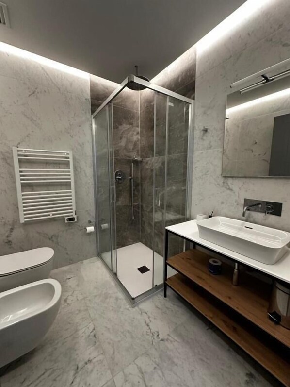 Une salle de bain moderne avec une douche à parois de verre, un lavabo blanc et des toilettes.