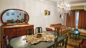 Ein Essbereich mit einem runden Tisch, Stühlen, einer Holzkommode, einem Spiegel und einer Chandelier.
