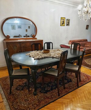 A dining area with a round table, chairs, a wooden cabinet, a mirror, and a patterned rug. - Rania apartment is located in the Hart of Heliopolis. (Cairo)