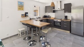 A modern kitchen with a wooden island, stainless steel appliances, and bar stools.