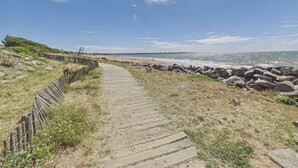 A wooden boardwalk leading to a beach with a rocky shoreline.