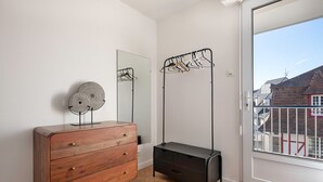 Una stanza con una cassettiera in legno, un tavolino consolle nero, uno specchio e un appendiabiti.