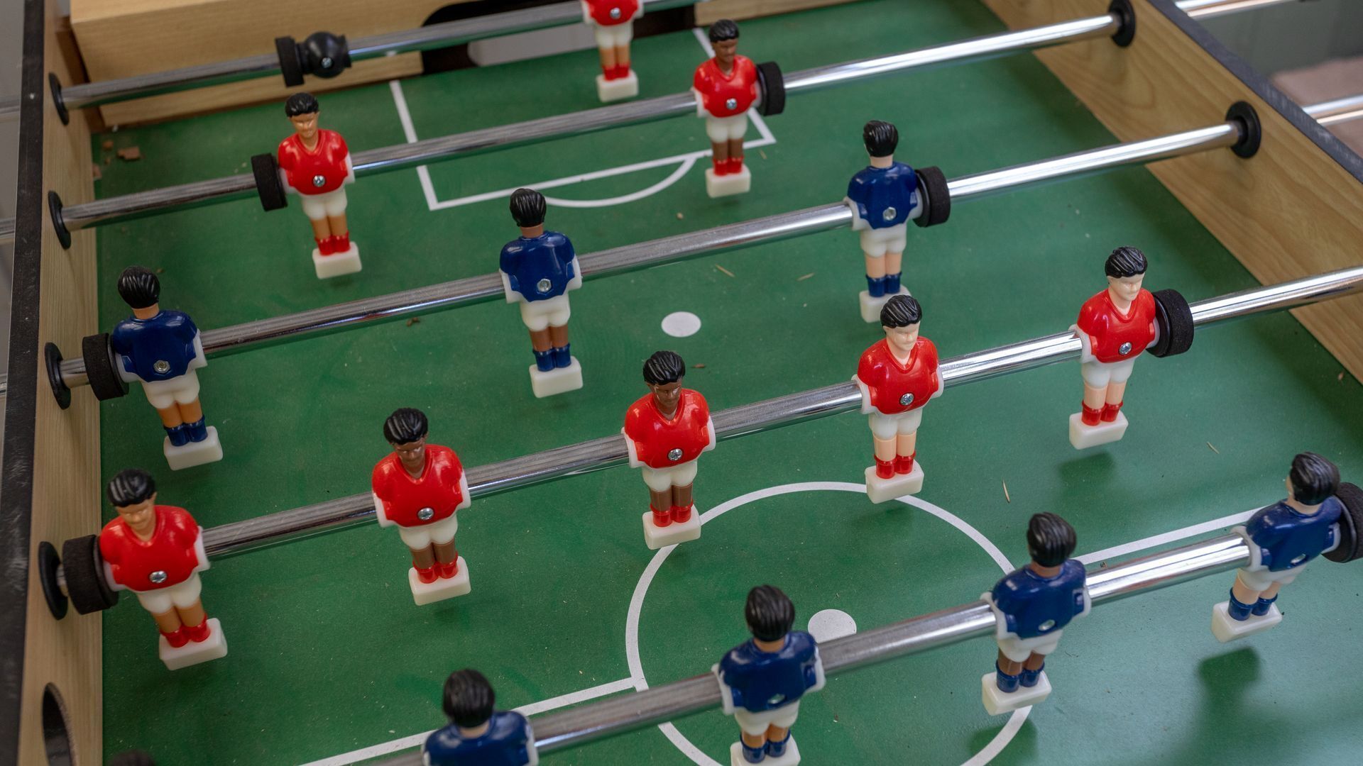 Ein Tischfußballspiel mit Spielfiguren in roten und blauen Trikots.