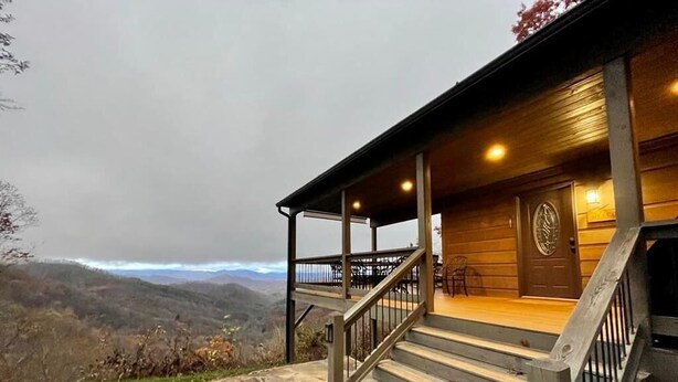 A wooden cabin with a stone staircase leading to a porch, overlooking a mountainous landscape. - Sunset Ridge Lodge - Sunset Ridge Lodge - Breathtaking mountain views and (Bryson City)