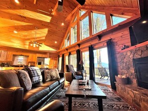 A cozy cabin interior with a wooden ceiling, a fireplace, a sofa, a dining table, and a kitchen area. - Tree Top Getaway close to Fontana Lake and NOC - Free Train Tix! (Almond)