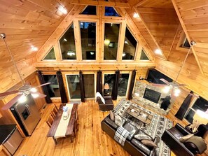 A cozy cabin with a dining area, a sofa, and a fireplace. - Tree Top Getaway - Tree Top Getaway close to Fontana Lake and NOC - Free Passes! (Almond)