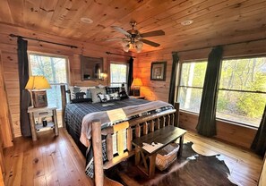 A cabin interior with a wooden bed, a ceiling fan, and a large window. - Tree Top Getaway close to Fontana Lake and NOC - Free Train Tix! (Almond)