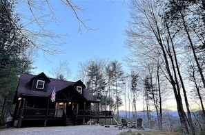 A cabin with a porch, a flag, and a view of the surrounding forest. - Tree Top Getaway close to Fontana Lake and NOC - Free Train Tix! (Almond)